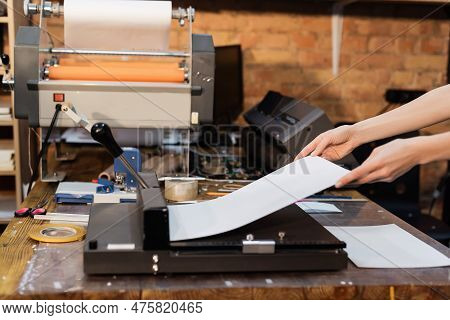 Cropped View Of Woman Holding Paper Near Paper Trimmer In Print Center.