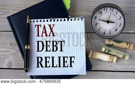 Tax Debt Relief - Words In A White Notebook On The Background Of An Alarm Clock And A Banknote. Busi