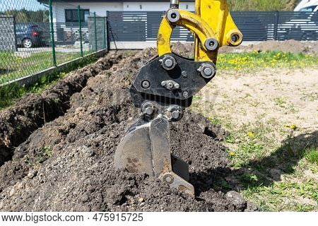 Mini Digger Digging A Hole In The Garden Along The Fence To The Drainage Pipes.