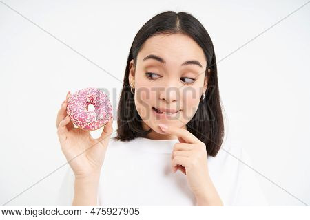 Close Up Of Cute Asian Girl Wants To Bite Tasty Doughnut, Thinking Of Trying Delicious Glazed Donnut