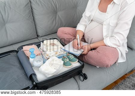 Pregnant Woman Is Getting Ready For The Maternity Hospital, Packing Baby Stuff. Pregnant Woman Prepa