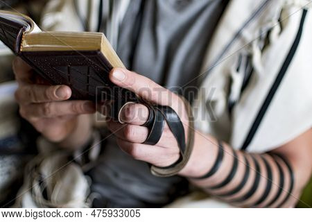 Reading Jewish Prayer And A Hand With Tefillin And Talit.