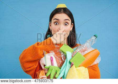 Portrait Of Woman Shuts Her Nose From Digust, Holding Stinky Garbage, Dirty Plastic Items And Empty 
