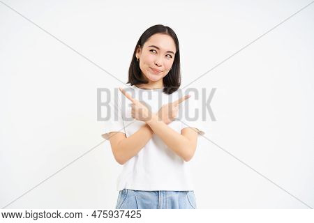 Thinking Asian Girl Makes Her Decision, Points Sideways, Two Ways, Choosing, Stands Isolated On Whit