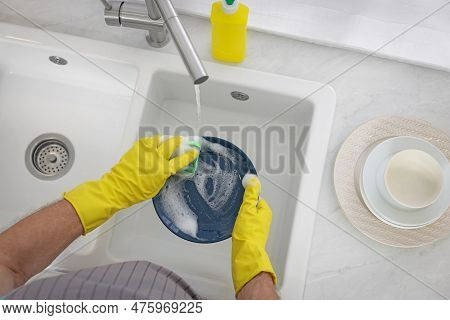 Man In Protective Gloves Washing Plate Above Sink Indoors, Top View