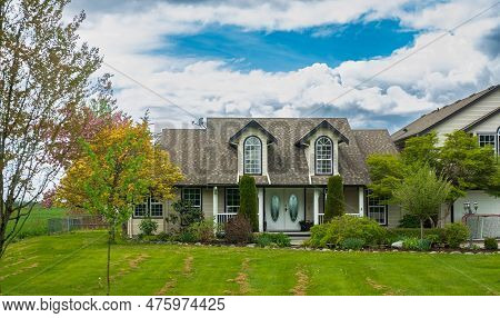Real Estate Exterior Front House On A Sunny Day. Big Custom Made House With Back Yard In The Suburbs