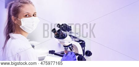A Young Woman Doctor (laboratory Assistant) Conducts A Study Of A Blood Sample On A Microscope.  Lot