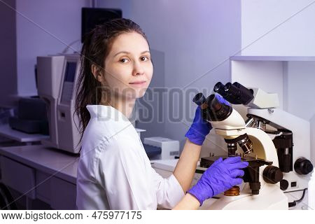 A Young Woman Doctor (laboratory Assistant) Conducts A Study Of A Blood Sample On A Microscope.  Sur