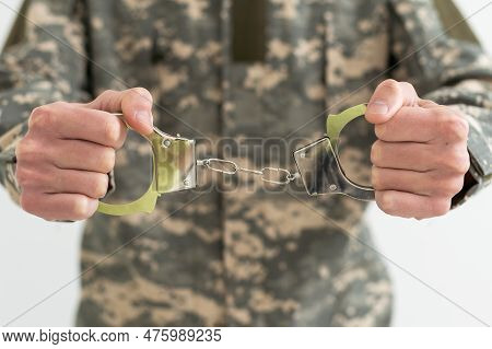 A Military Man In Handcuffs Holds An Army Badge In His Hand On A Dark Background, Selective Focus. C