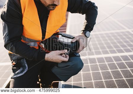 Worker Is Fixing Solar Panels And Opening Toolbox While Crouching On The Rooftop.