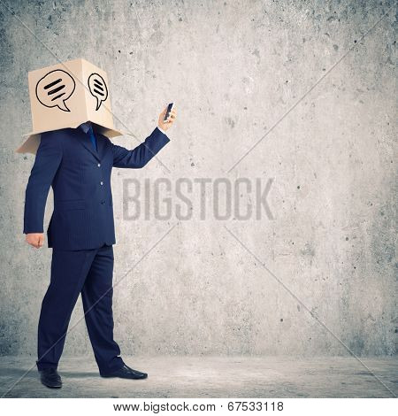 Businessman using mobile phone wearing carton box on head