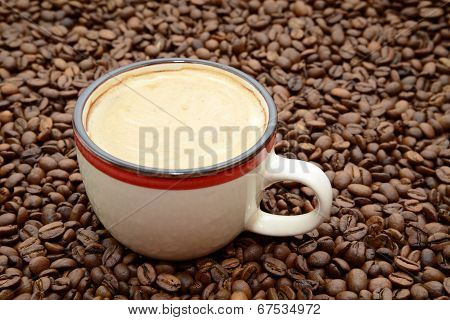cup of coffee with cream on a coffee beans background