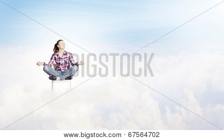 Young woman sitting on chair and meditating