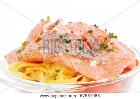 fresh fried natural pink salmon on italian traditional tagliatelle backed with tomato and vegetables isolated over white background