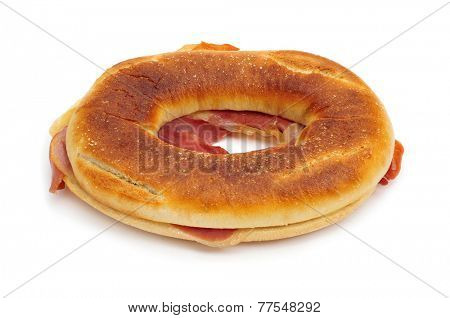 a spanish rosca de jamon serrano, a donut-shaped serrano ham sandwich, on a white background