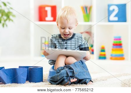 smiling child sitting on chamber pot with toilet paper