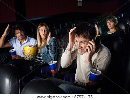 Spectators shouting at man using mobilephone while watching film in movie theater
