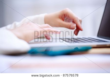 Close-up shot touching laptop trackpad. Focused on fingers at trackpad