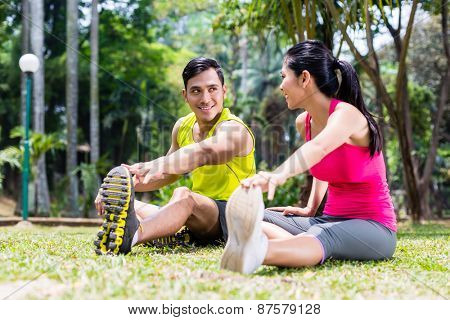 Asian woman and man, a couple, during gymnastics stretching for sport fitness in tropical park