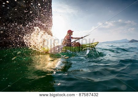 Young lady paddling hard the sea kayak with lots of splashes
