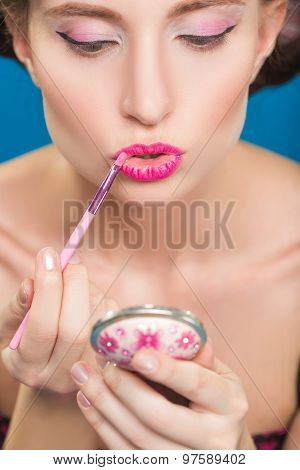 Sexy young pin-up girl doing make-up