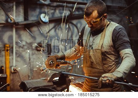 worker sawing metal with a saw sparks fly