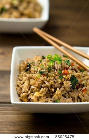 Fried rice. Basil chicken fried rice with chopsticks on a wooden background viewed from above. This thai inspired meal is perfect for a quick lunch or served as side dish.