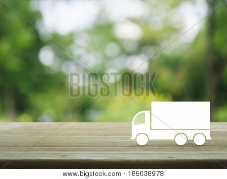 Truck flat icon on wooden table over blur green tree background Business transportation service concept
