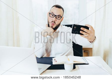 Portrait of a business man doing a selfie on a mobile phone in the workplace