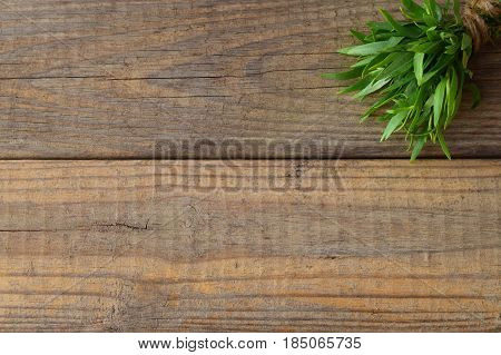 Bunch of fresh tarragon on a wooden background with a space for note