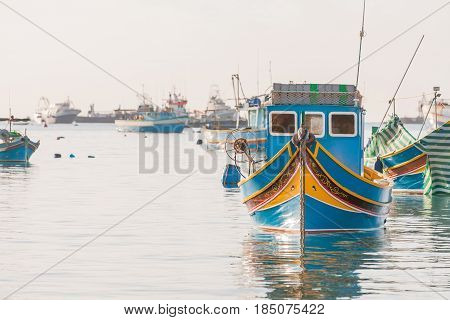 Mediterranean traditional colorful boats luzzu. Fisherman village in the south east of Malta. Early winter morning in Marsaxlokk Malta.