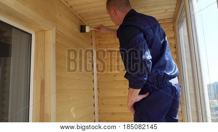 young worker varnishing the wooden surfaces of the walls of the balcony.