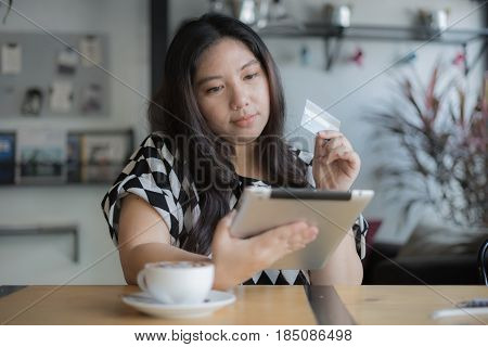 woman shopping online using credit card visa card laptop tablet in coffee shop happy face / woman shopping online credit card