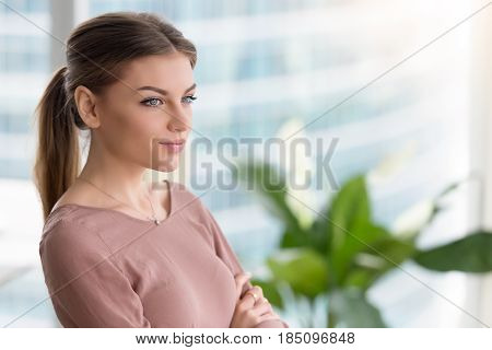 Head shot portrait of pensive young woman at home office interior with arms crossed, looking at the window, dreaming of future, thinking about something, lost in thoughts and ideas, copy space