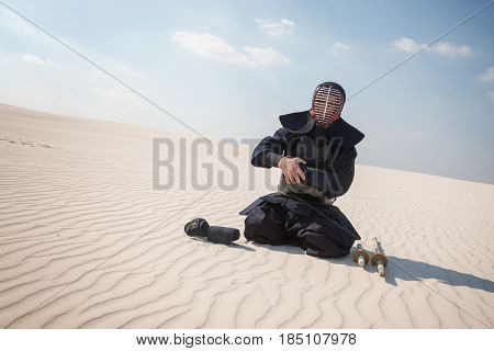 Warrior, Man In Traditional Armor, Bogu For Kendo Sits  In A Desert