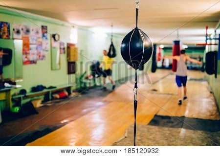 Punching bag in the shape of a ball in the gym. Against the backdrop of athletes.