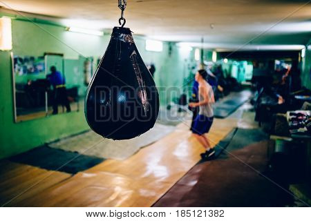 A boxer guy is wearing a Punching bag in the gym. Against the backdrop of athletes. Gym is a cellar. Russia.