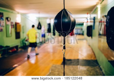 Punching bag in the shape of a ball in the gym. Against the backdrop of athletes.