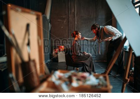 Male artist work with female poseur in art studio