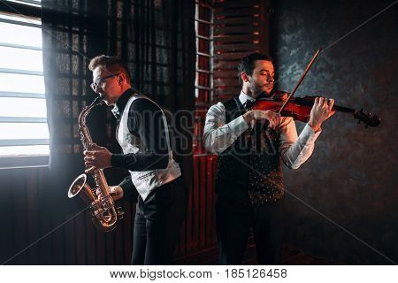 Sax man and fiddler duet playing classical melody
