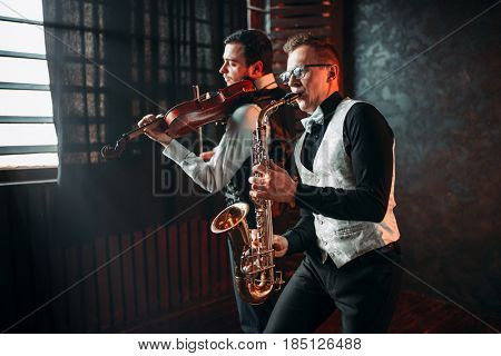 Sax man and fiddler duet playing classical melody