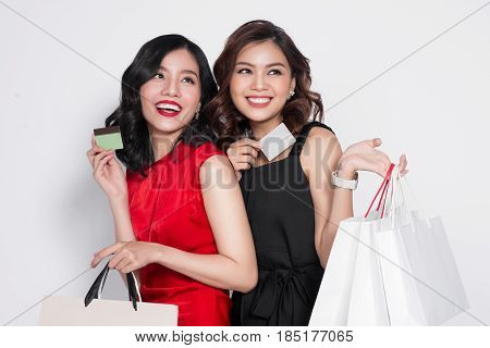 Two Happy Attractive Young Women With Creadit Card Holding Shopping Bags On White Background