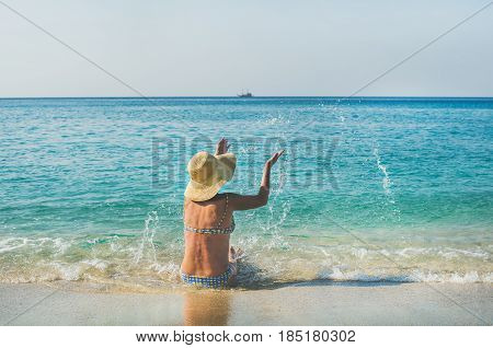 Beautiful slim senior woman tourist in bikini sitting on sand enjoying sea at Meditteranean resort of Turkey in Alanya, Kleopatra beach
