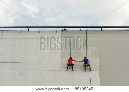 Un safety Painters and harnesses hanging high building in construction sitehand brush color work concept