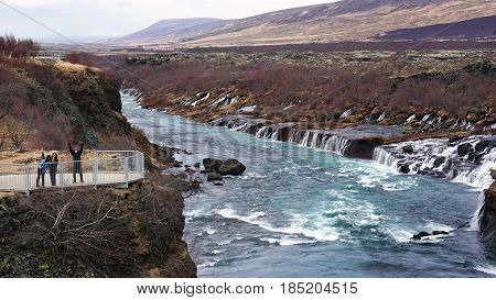 Happy Asian Family Travelers At Hraunfossar Waterfall In Iceland