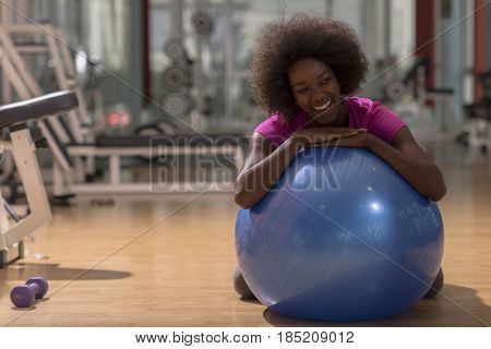 happy african american woman with a curly afro hairstyle in a  gym relaxing after pilates workout