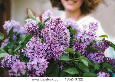Hands of a girl with a large bouquet of lilacs. Focus on the lilacs