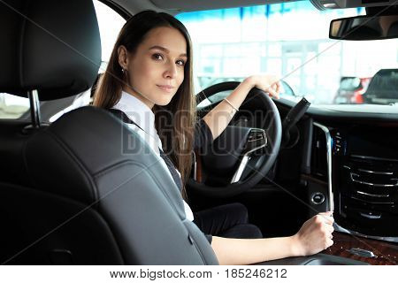 Smiling woman sitting in a car and looking back.