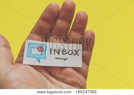 Male hand with a piece of paper and the word : Inbox message on a yellow background. Social media and network concept