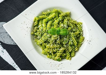 Rotini pesto pasta top view. Rotini pasta with basil pesto sauce grated parmesan cheese and fresh pepper. This Italian dish makes a delicious meal by itself or can be used as a pasta salad side.